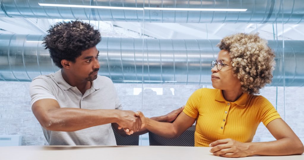 Two office afro workers shake hands approving a contract or agreement.