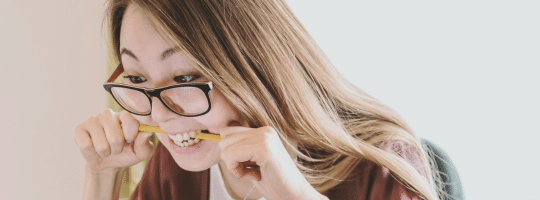 woman biting pen looking at screen