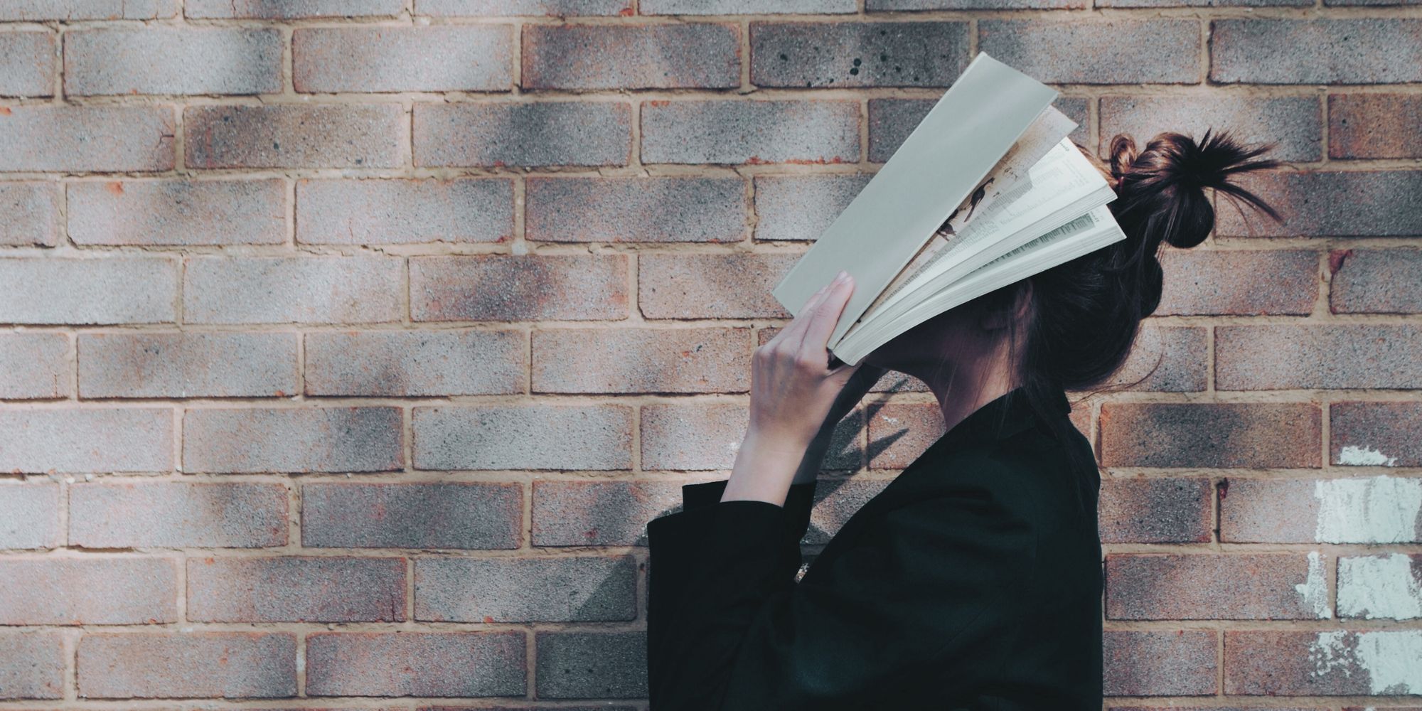 woman standing with book over her face thinking about hecs debt